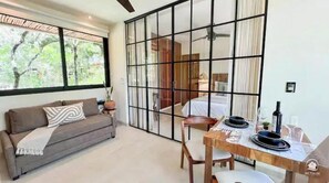 A modern room with a sofa, dining table, and a large window. - New Studio APT 5 min by car from Tulum Beach ᯽B1 (Tulum)