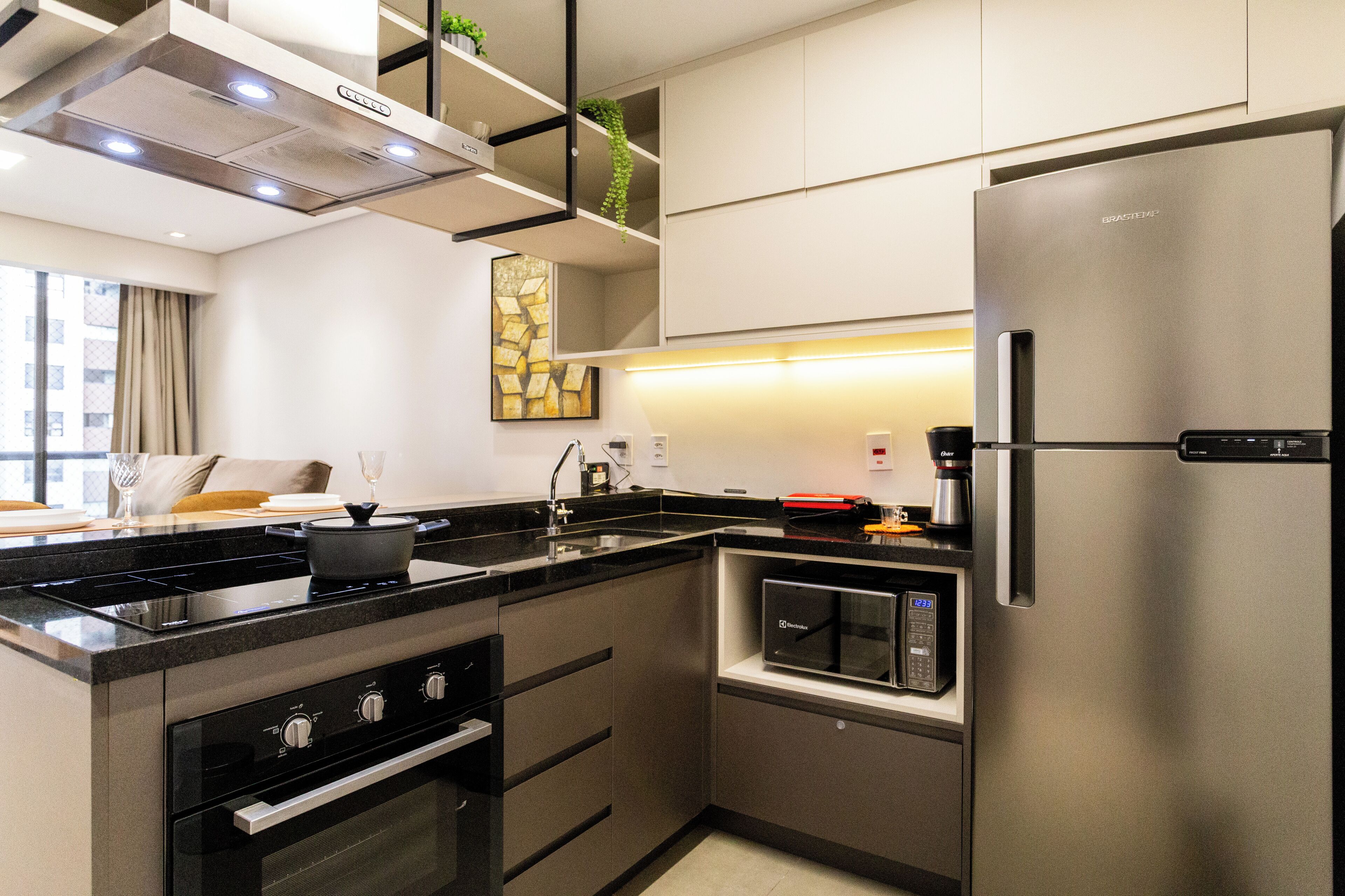 A modern kitchen with a stainless steel refrigerator, built-in oven, and a microwave.
