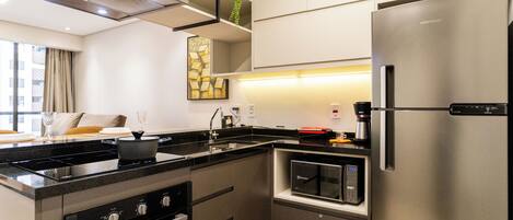 A modern kitchen with a stainless steel refrigerator, built-in oven, and a microwave.