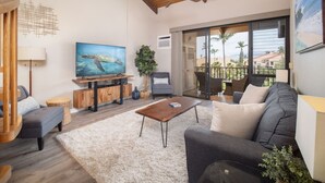 Una sala de estar con sofá, mesa de centro, televisor y un balcón con vistas.