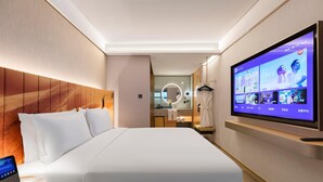 A modern hotel room with a large bed, a TV mounted on the wall, a bedside table, and a bathroom visible through an open door. - Manxin Hotel Shanghai Hongqiao Airport Internation (Shanghai)