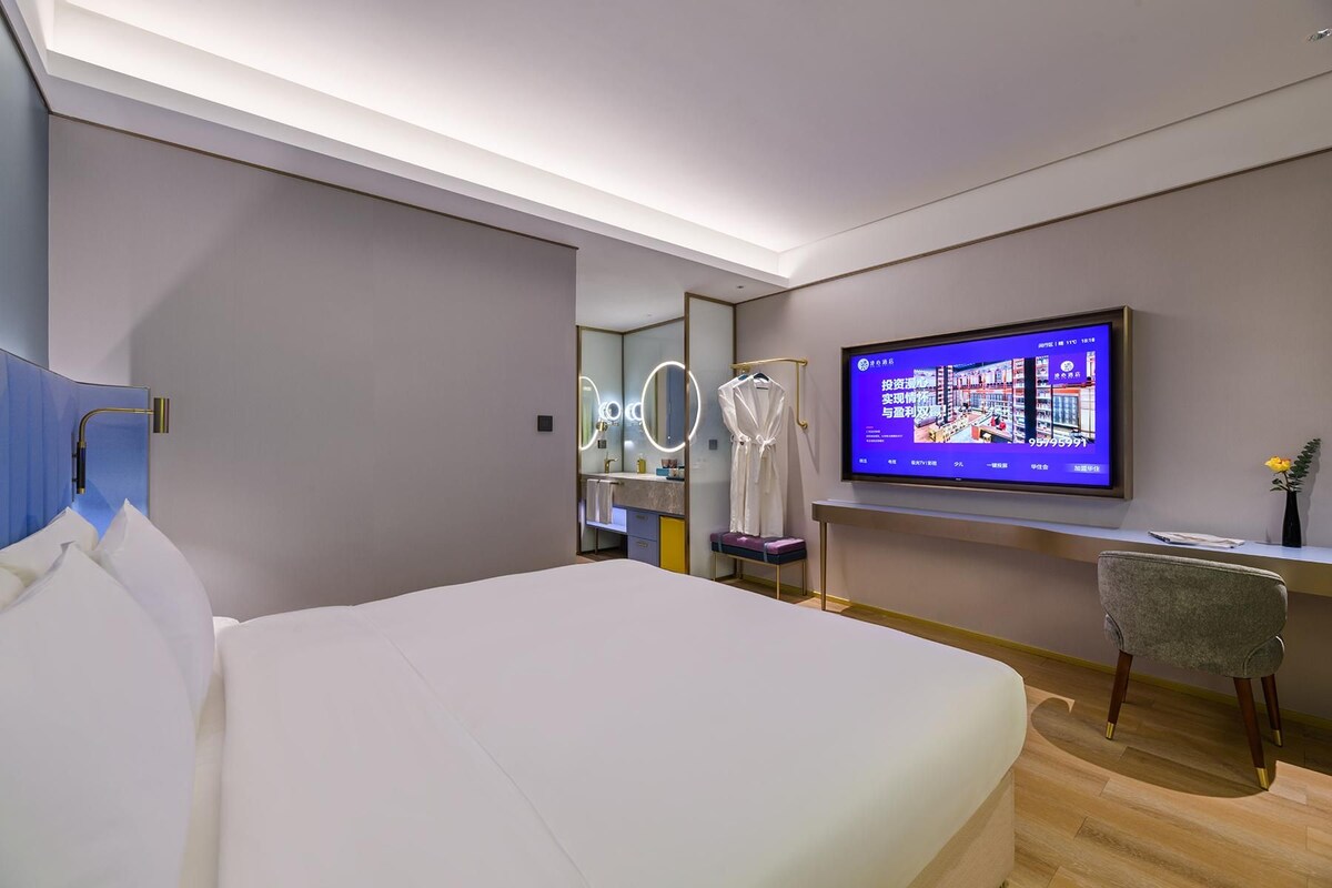 Une chambre d’hôtel moderne équipée d’un grand lit, d’un bureau avec une chaise, d’une télévision et d’un miroir.