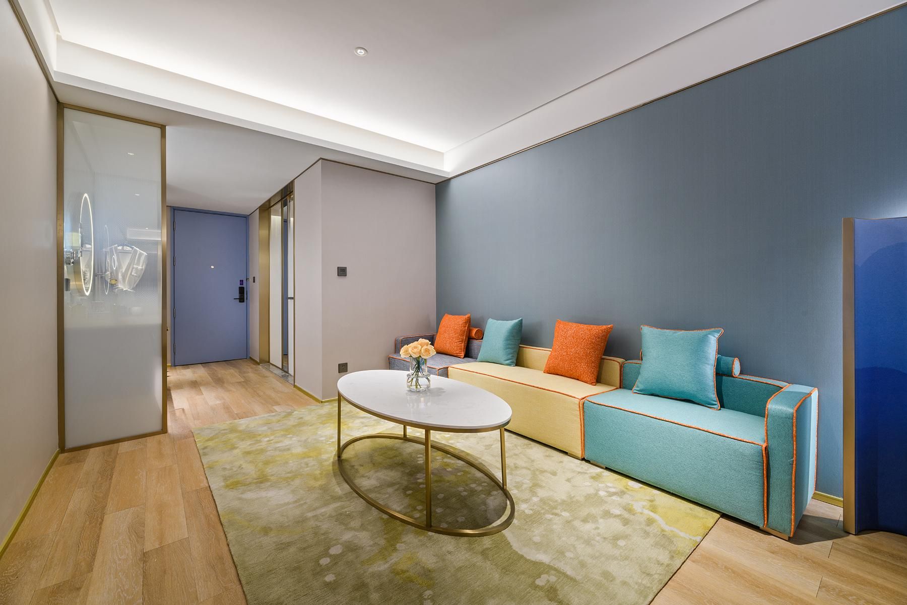 A modern living room with a sofa, a coffee table, and a glass door leading to another room.