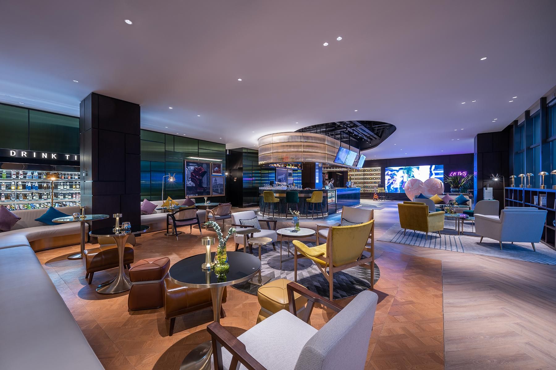 A modern lounge area with a bar, seating arrangements, and a display of liquor bottles.