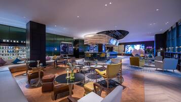 A modern lounge area with a bar, seating arrangements, and a display of liquor bottles.