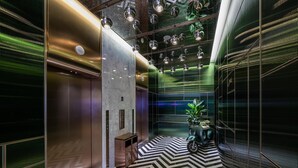 A modern elevator with a metallic finish and a black and white chevron-patterned floor. - Manxin Hotel Shanghai Hongqiao Airport Internation (Shanghai)