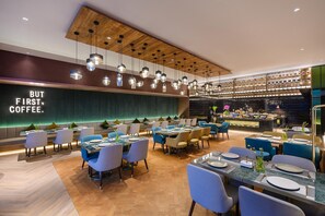 Un restaurant moderne doté de plusieurs tables et chaises, d’un bar et d’un mur orné d’une citation inspirante.