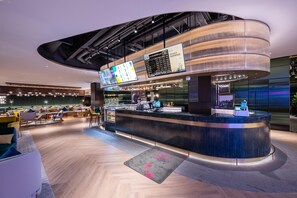 Un espace bar moderne doté d’un comptoir incurvé, de sièges et d’un écran numérique affichant le menu.