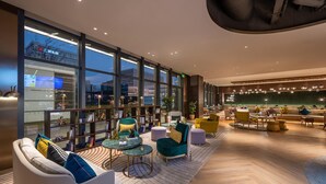 A modern lounge area with seating, tables, and large windows offering views of the cityscape. - Manxin Hotel Shanghai Hongqiao Airport Internation (Shanghai)