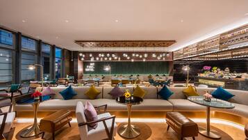 A modern lounge area with sofas, tables, and a bar with decorative items.