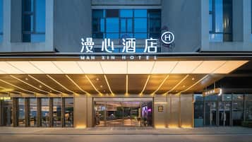 The exterior of the Man Xin Hotel with a modern facade, large glass windows, and a prominent entrance.