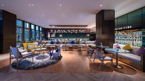 A modern lounge area with seating arrangements, a bar area with a drink menu, and a view of the city through large windows. - Manxin Hotel Shanghai Hongqiao Airport Internation (Shanghai)