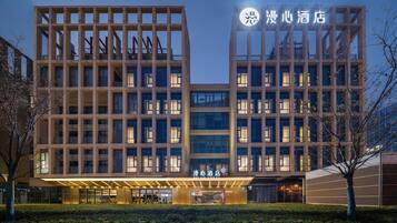 A modern hotel building with a symmetrical facade, multiple floors, and a well-lit entrance.