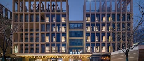 A modern hotel with a symmetrical facade, multiple floors, and a well-lit entrance.