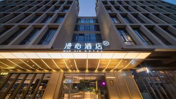 A hotel entrance with a modern design, featuring a prominent sign and a glass facade.