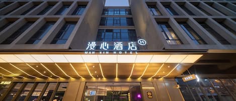 A hotel entrance with a modern design, featuring a prominent sign and a glass facade.