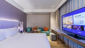 A modern hotel room with a large bed, a seating area with a small table and chairs, and a television displaying a menu. - Manxin Hotel Shanghai Hongqiao Airport Internation (Shanghai)