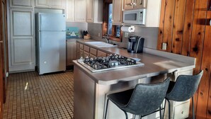A kitchen with white cabinets, a stainless steel refrigerator, a microwave, a coffee maker, and a gas stove. - Lakefront cottage on 540 acre Wall Lake / spectacular fishing & sunset views.  (Delton)