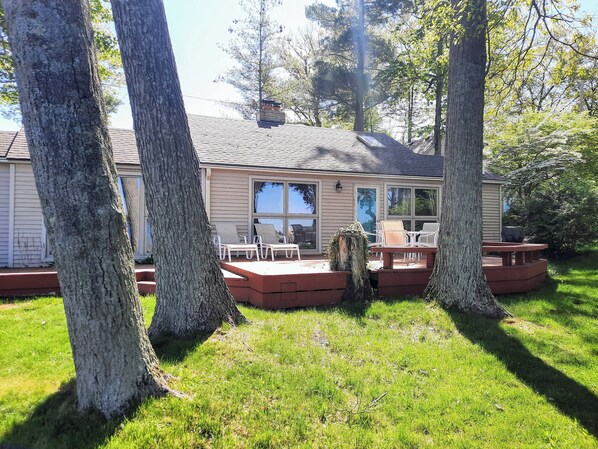 A house with a covered patio, outdoor seating, and a large window overlooking the yard.