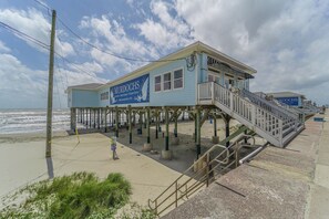 A beachside building with a sign advertising Murdoch's, a family-owned business since 1910, offering souvenirs, beachwear, and frozen drinks.