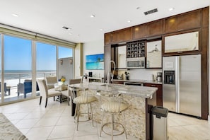 A modern kitchen with a large island, stainless steel appliances, and a view to the outside. - XL Terrace, Lazy River, I-O Pools, Game Room, Spa, Beach, Luxury 2-2 Penthouse! (Galveston)