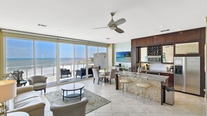 Een moderne keuken met een groot eiland, een eethoek met uitzicht en een balkon dat uitkijkt op de oceaan.