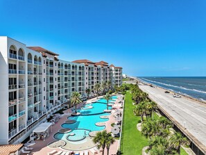 A hotel with multiple balconies, a large central pool, and a view of the ocean. - XL Terrace, Lazy River, I-O Pools, Game Room, Spa, Beach, Luxury 2-2 Penthouse! (Galveston)