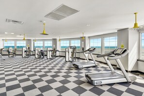A gym with cardio equipment, weight machines, and large windows with a view.