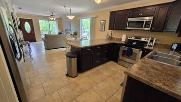 A modern kitchen with dark cabinetry, stainless steel appliances, and a granite countertop.