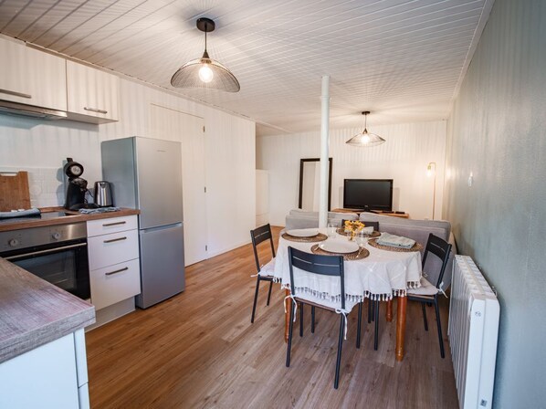 A compact kitchen with modern appliances, a dining area with a round table, and a large window.