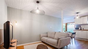 Un salon moderne avec un canapé, un pouf et un plancher en bois.