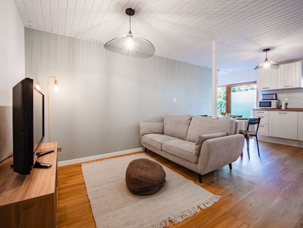 Una sala de estar moderna con sofá, reposapiés y piso de madera.