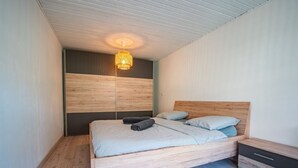 Une chambre moderne avec un lit en bois, une table de chevet et un luminaire suspendu.