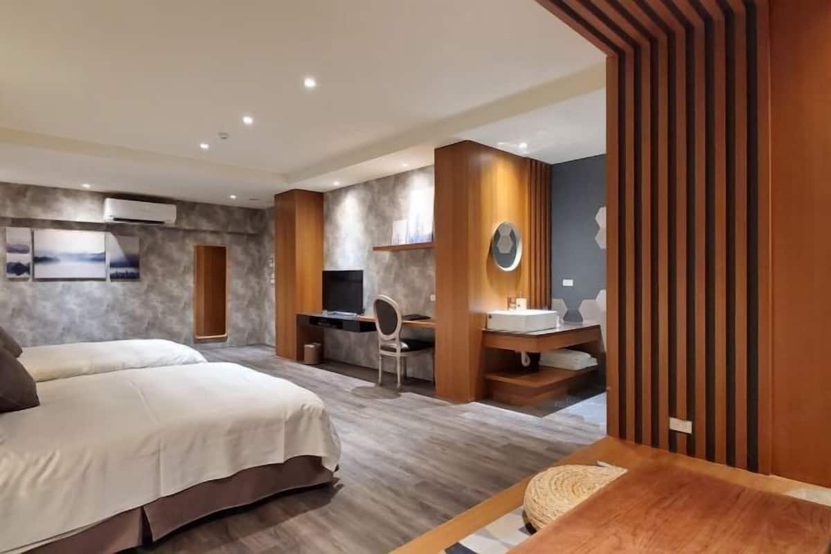 A modern hotel room with a large bed, a desk, a chair, and a vanity with a mirror.