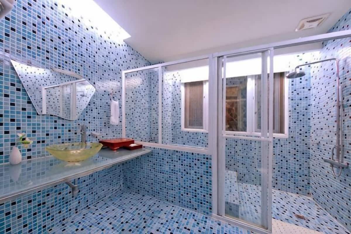 Un baño con cabina de ducha de vidrio, un lavabo y una pared con azulejos.