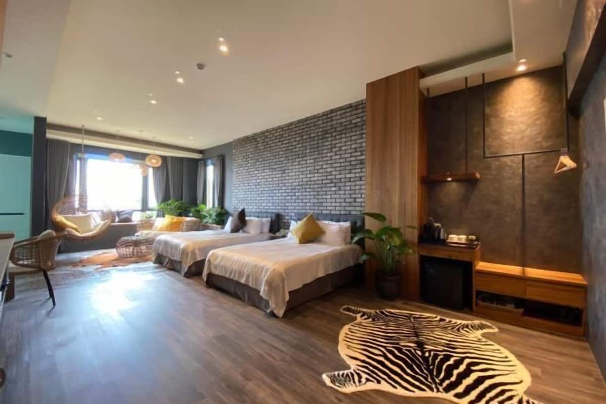 A modern hotel room with two beds, a zebra rug, and a brick wall.
