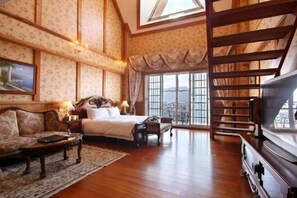A room with a bed, a sofa, a TV, and a staircase.