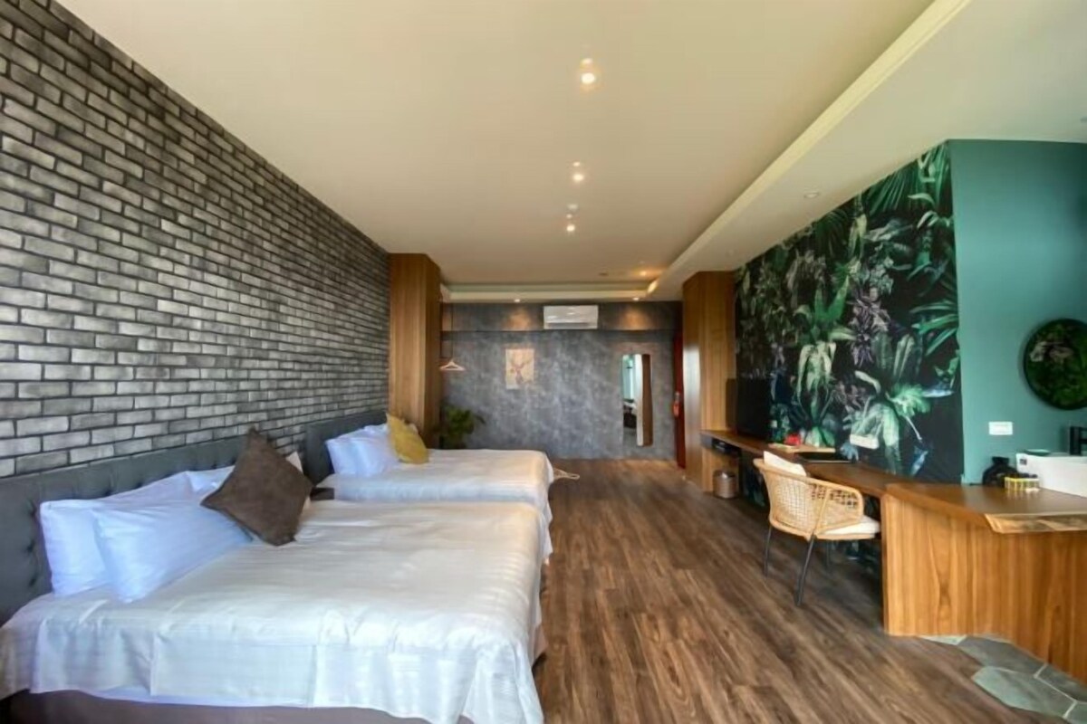 Quarto de hotel com duas camas, uma receção e um grande mural na parede.
