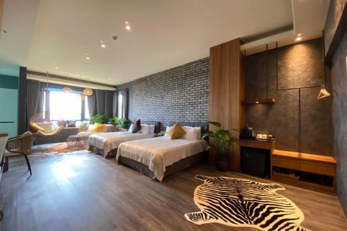 A modern hotel room with two beds, a zebra rug, and a brick wall.