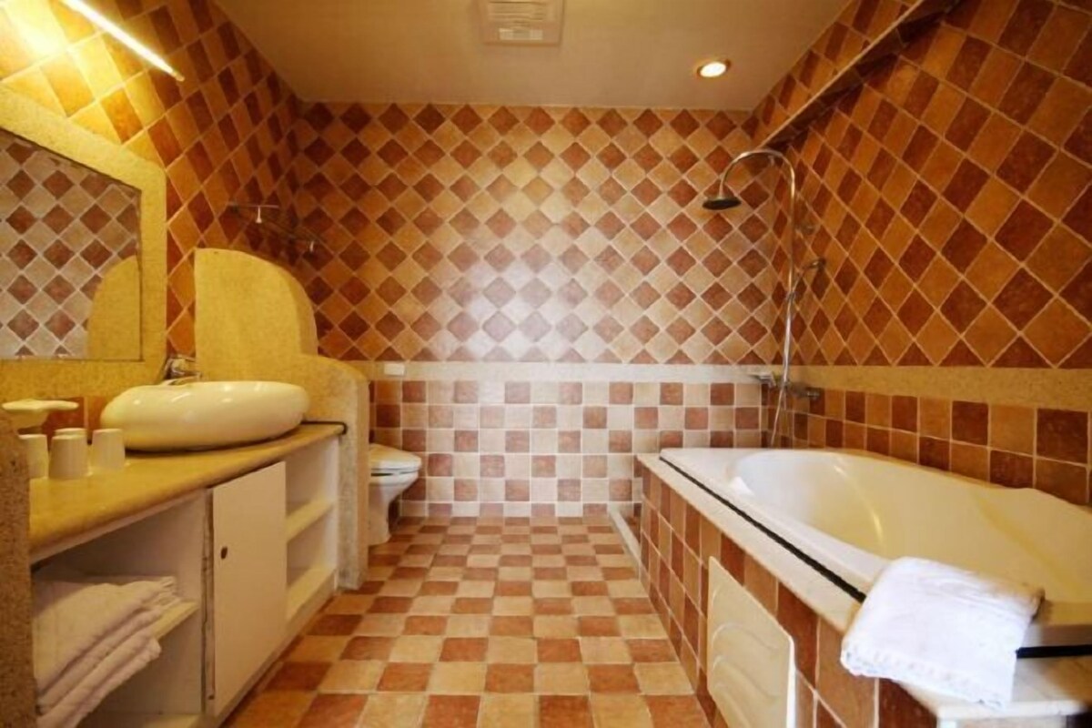 A bathroom with a checkered floor, a sink, a toilet, and a bathtub.