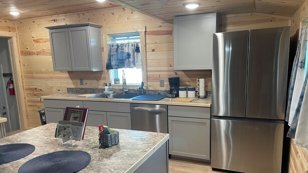 Una cocina moderna con paredes de madera, un refrigerador de acero inoxidable y una encimera de granito.