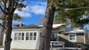Una casa de dos pisos con fachada de piedra y exterior blanco, y una chimenea.