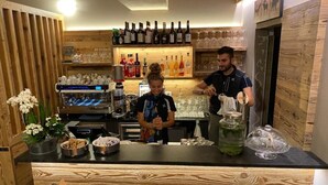 Un espace bar avec des meubles en bois, un comptoir où sont exposées des bouteilles, et une personne en train de servir une boisson.