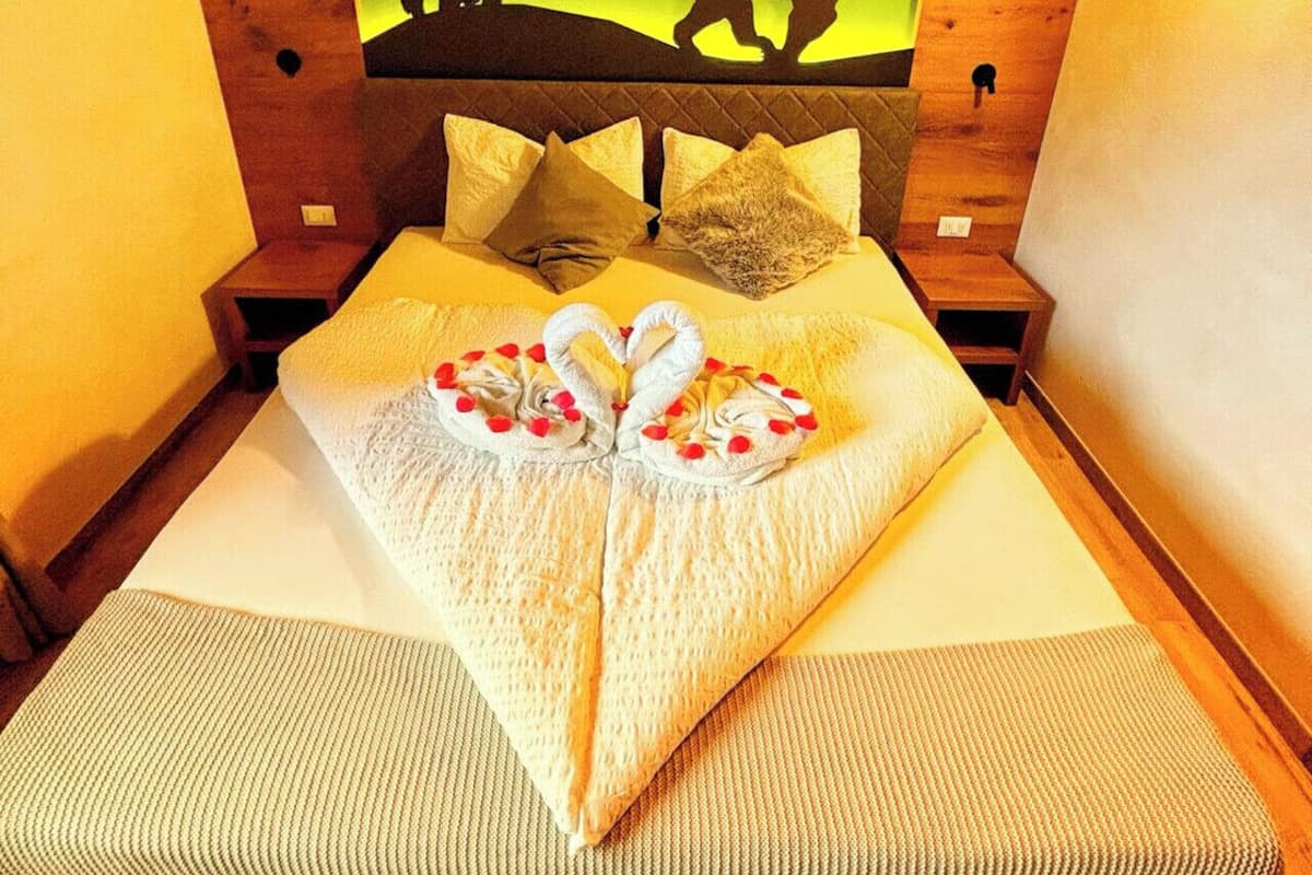 A room with a bed, wooden headboard, and a wall mural of animals.