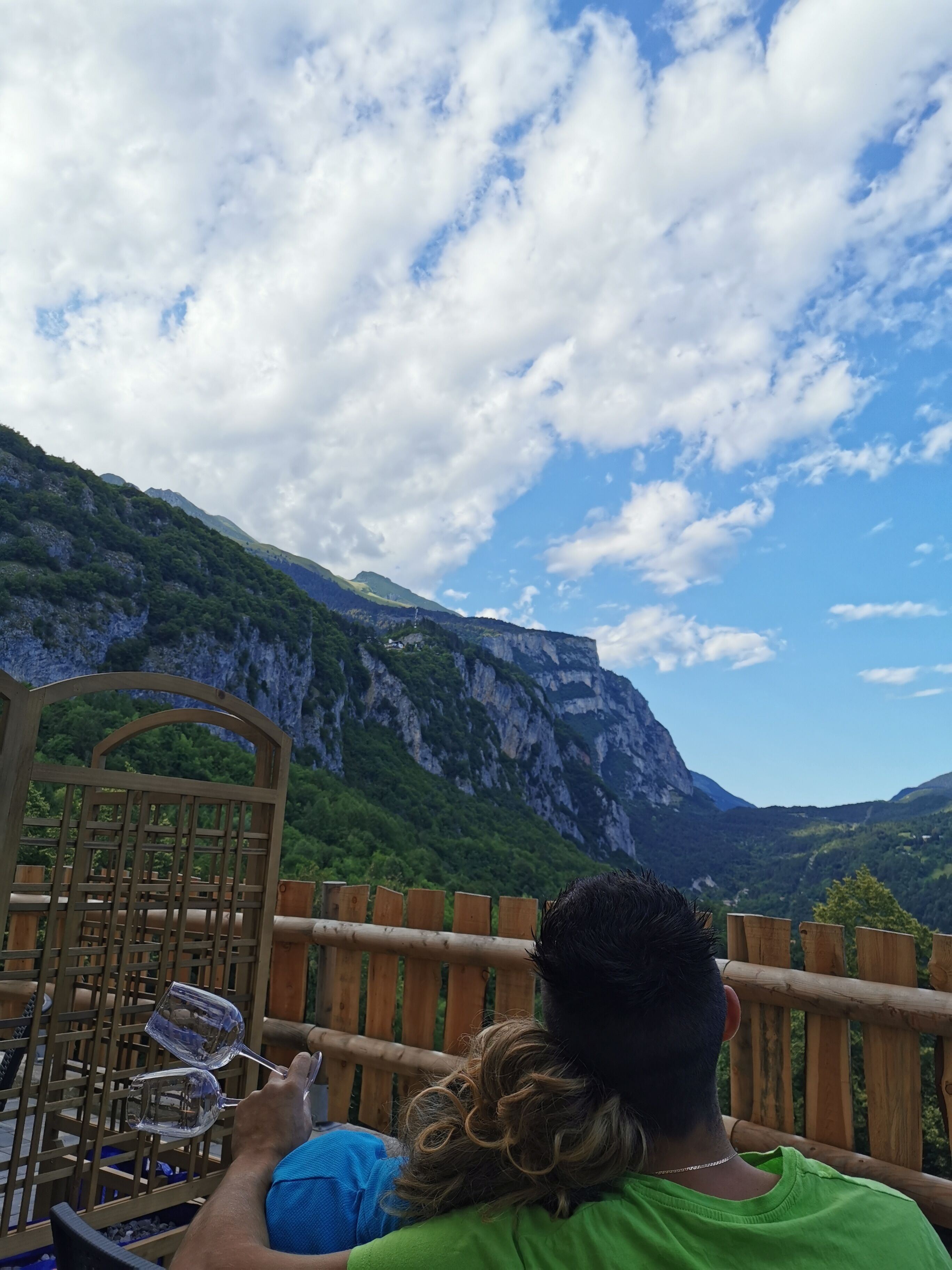 A couple seated at a wooden table with a mountain view.
