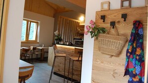 Un intérieur en bois comprenant un coin cuisine, des tabourets de bar et une table à manger.