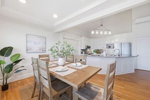 Un comedor con una mesa de madera, sillas y una planta en maceta.