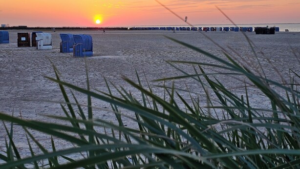 A beach with portable toilets and a sunset in the background. - Ferienhaus Meeresbrise in Nessmersiel - NEU in der Vermietung (Dornum)