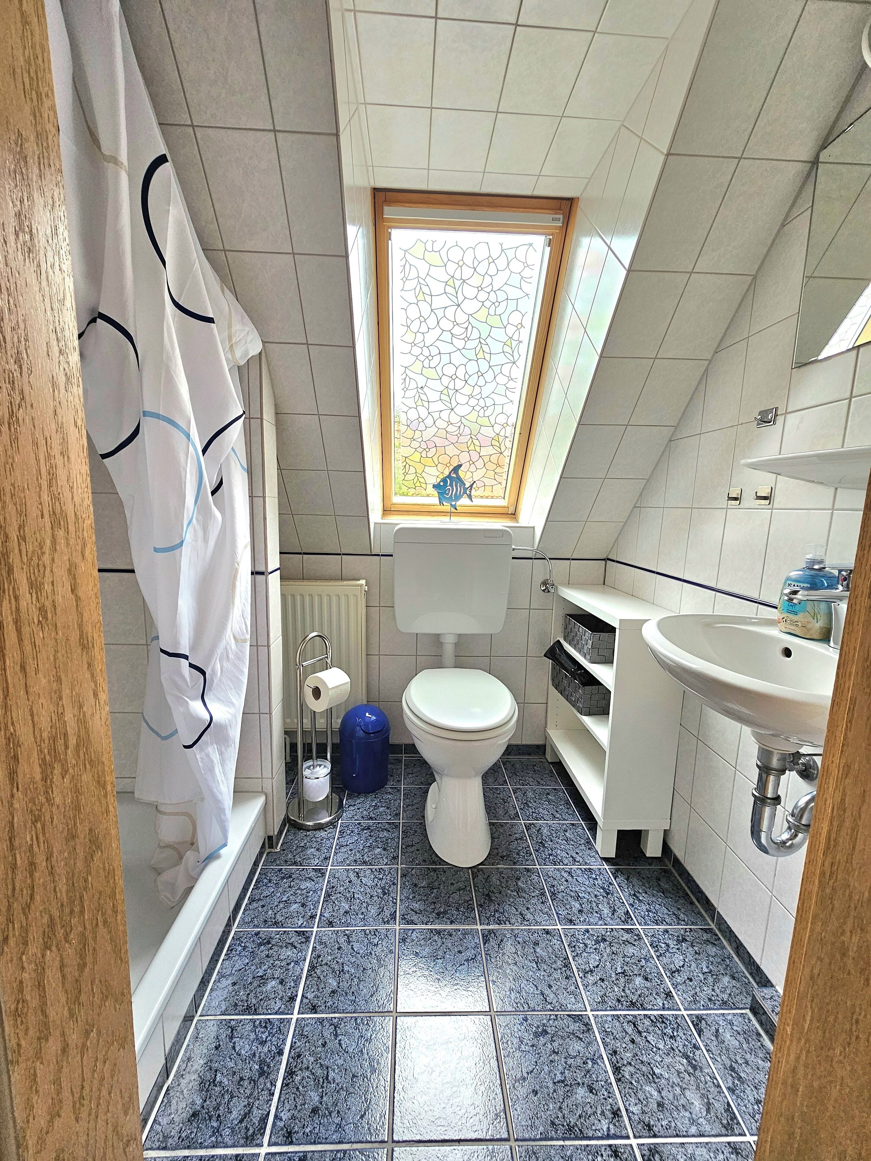 A small, compact bathroom with a toilet, sink, and shower area.