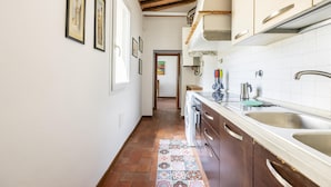 Una cocina estrecha con armarios de madera, salpicadero de azulejos y un tapete estampado.